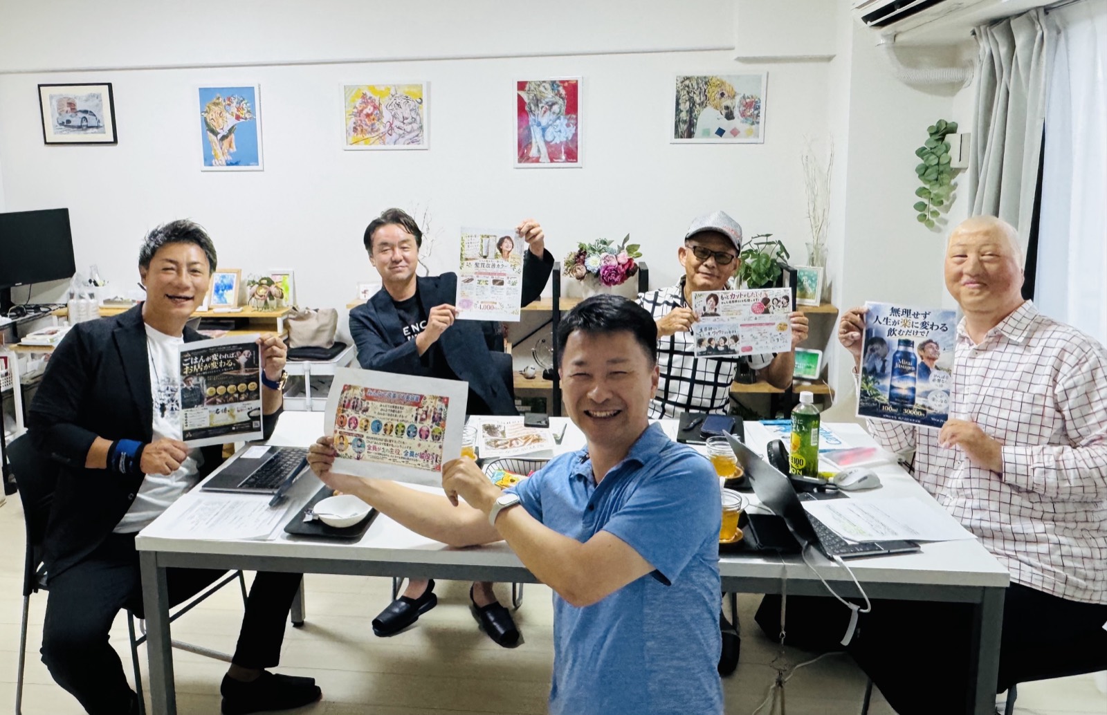 ワークショップ終了時、参加者4名がそれぞれ完成したチラシを手に持って並んでいる。中央が講師の伊藤ゆきひろ