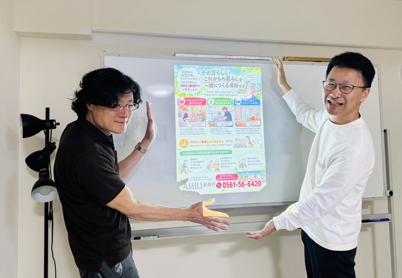 完成したチラシを映したホワイトボードの前で、参加者と講師が笑顔で並んでいる写真
